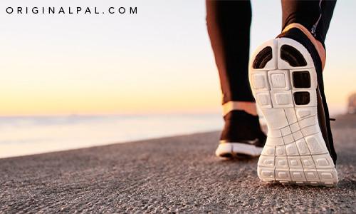 زیره کفش ورزشی در پای دونده به سمت غروب آفتاب